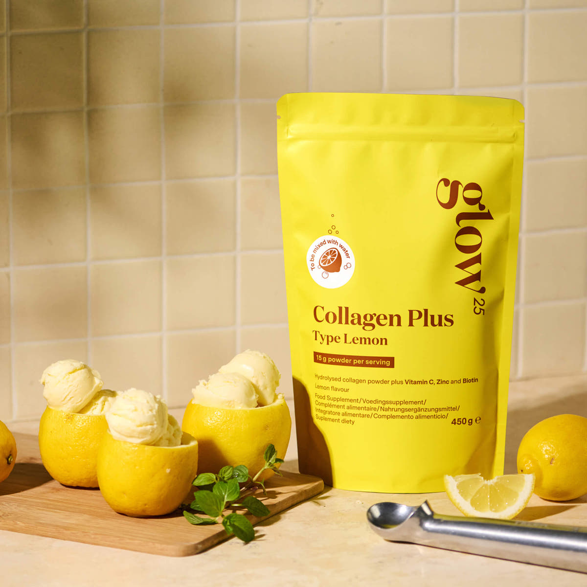 Pouch of Glow25 Collagen Plus Type Lemon beside lemon sorbet scoops and fresh lemons