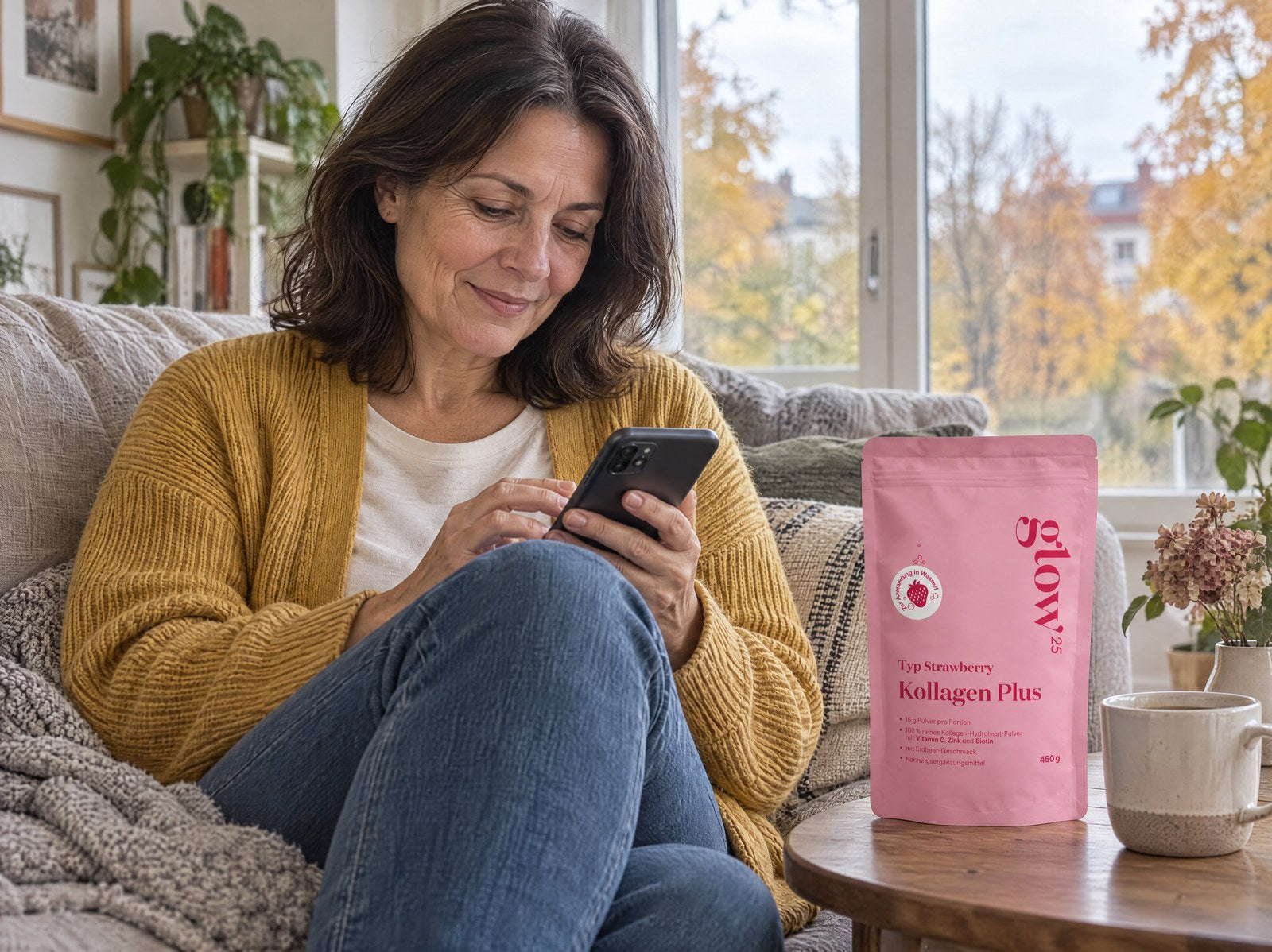 Donna con un cardigan color senape sul divano sceglie sul telefono la sua prossima consegna, accanto Collagen Plus tipo Strawberry
