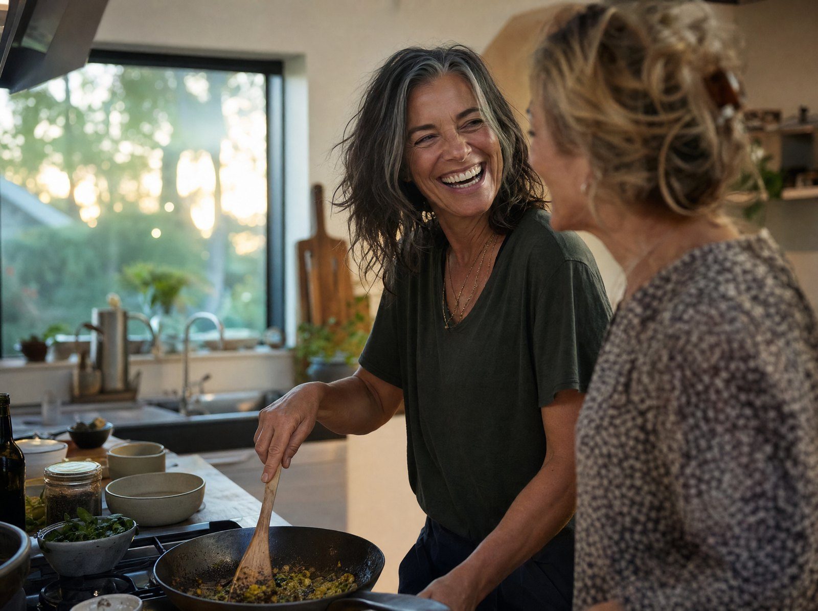 Frau um 50 lacht abends beim Kochen mit einer Freundin, voller Energie