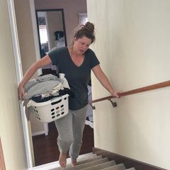 Frau trägt einen Wäschekorb die Treppe hoch